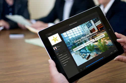 Persona visualizza un corso e-learning creato con Articulate Studio '13 su tablet durante una riunione