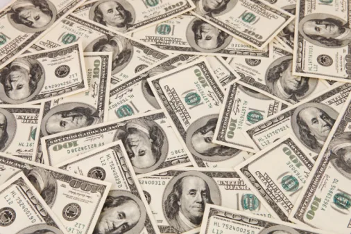 Numerose banconote da cento dollari americani sparse, simbolo di valuta in un contesto globale di localizzazione elearning