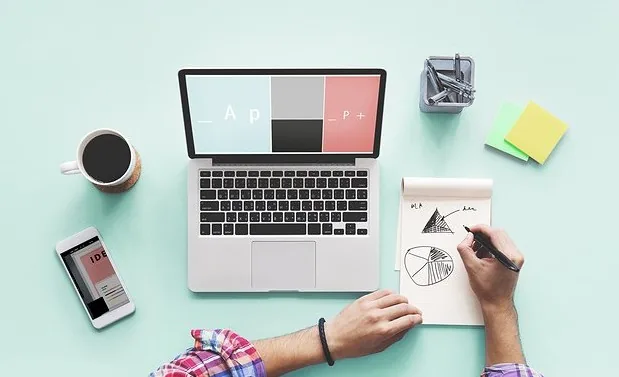 Scrivania con laptop, blocco note con grafici a torta e palette colori, strumenti per progettare corsi eLearning coerenti
