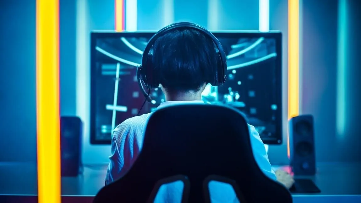 Persona con cuffie davanti a un monitor luminoso in un ambiente digitale, simbolo di coinvolgimento audio nell’eLearning