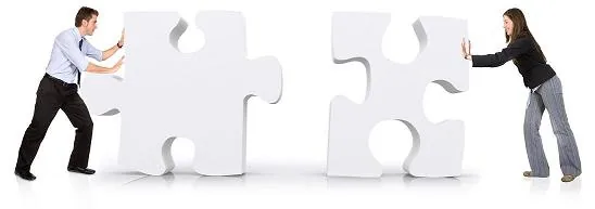 Due persone in abiti formali spingono grandi pezzi di puzzle per simboleggiare collaborazione nella formazione aziendale