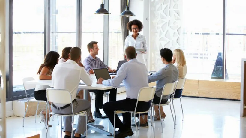 Un gruppo di colleghi discute attorno a un tavolo moderno, simbolo di collaborazione nella formazione online aziendale