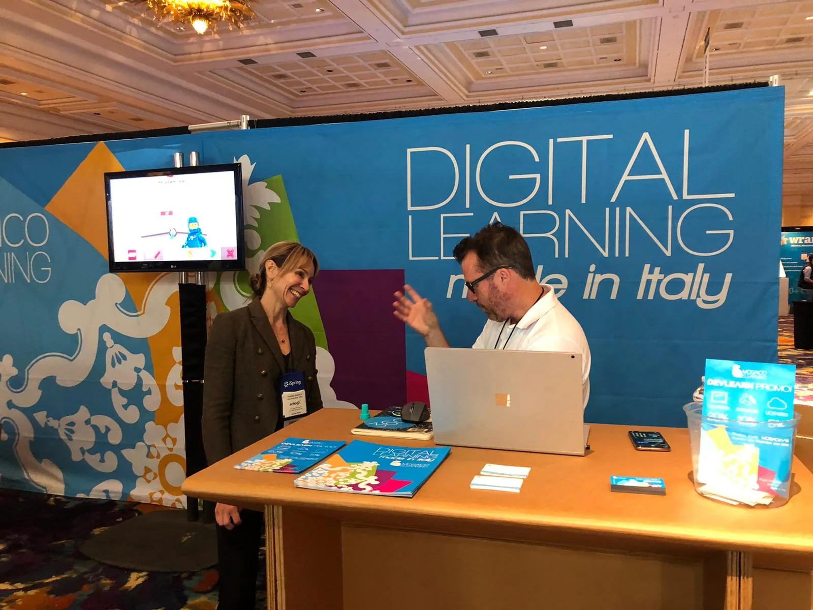 Due persone dialogano davanti allo stand Mosaico eLearning dedicato al digital learning made in Italy