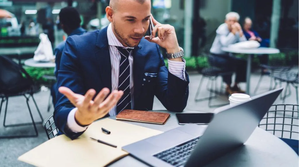 Professionista che usa smartphone e laptop insieme in un ambiente esterno, simbolo delle distrazioni nel mobile learning