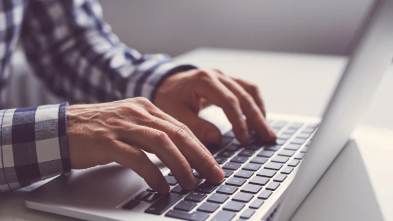 Mani di una persona che digitano su una tastiera di laptop, simbolo di formazione eLearning per il management aziendale