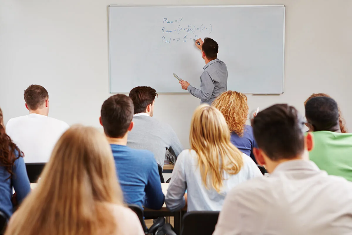 Formatore che spiega concetti tecnici a un gruppo di adulti in aula durante un corso di formazione