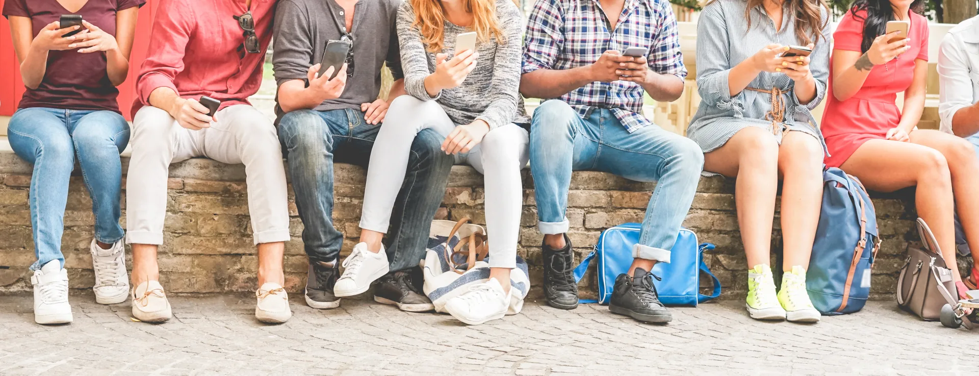 Gruppo di giovani seduti all’aperto che utilizzano smartphone, simbolo della Generazione Z digitale e connessa