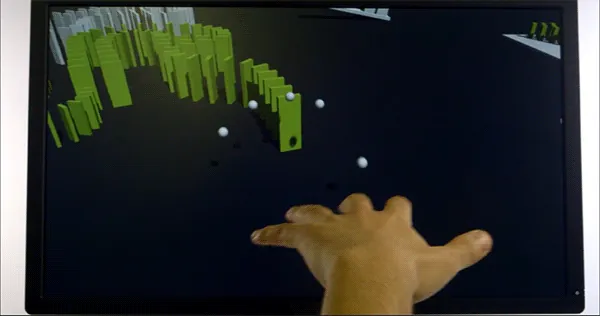 Mano che interagisce con schermo virtuale dove cadono tessere verdi in uno scenario simulato di apprendimento