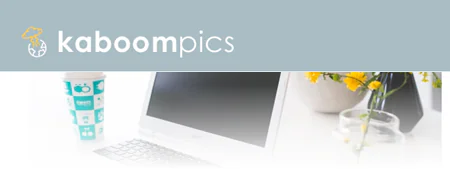 Logo Kaboompics con laptop, tazza e fiori, rappresenta una risorsa di immagini gratuite per corsi e-learning