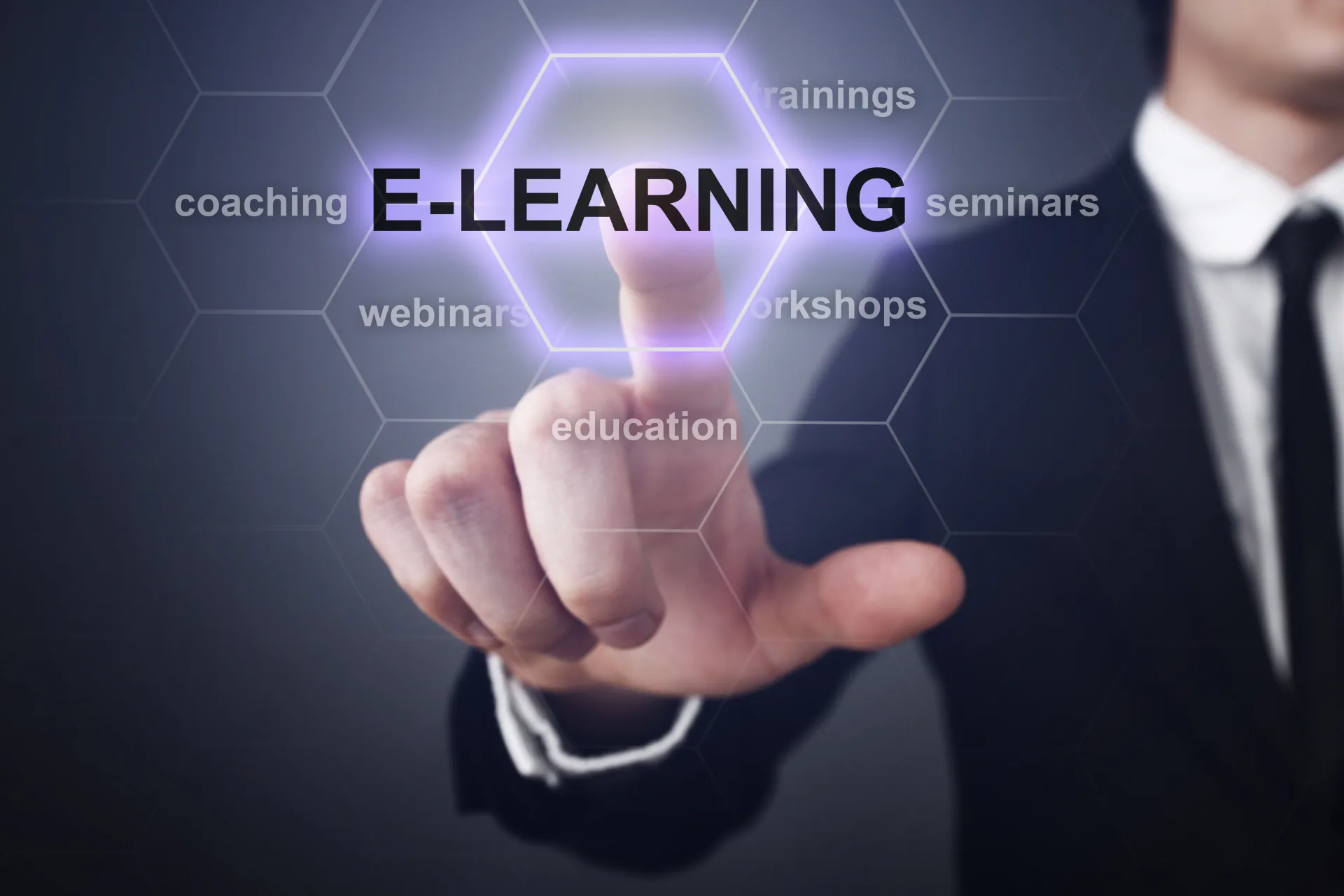 Persona in abito professionale tocca la parola e-learning su uno schermo virtuale con termini legati alla formazione digitale