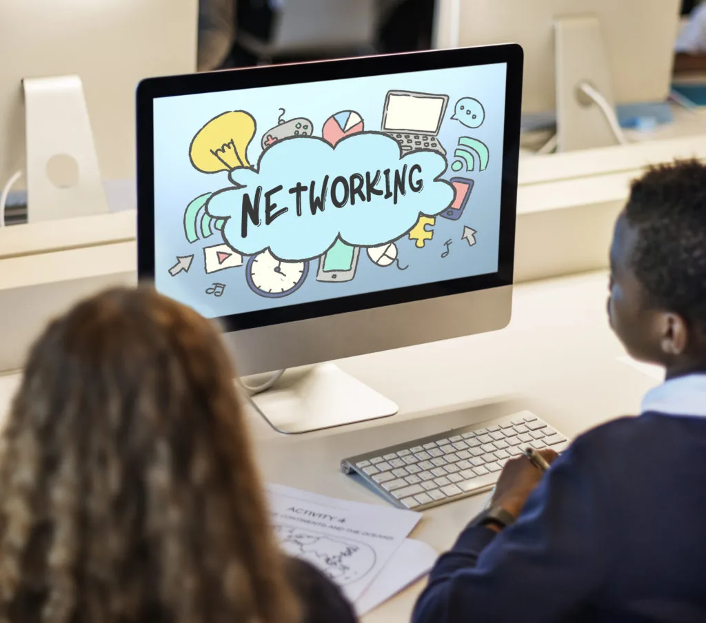 Due studenti guardano un monitor con la scritta networking e icone di social media, tema e-learning