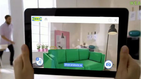 Tablet mostra un divano virtuale verde in una stanza reale con realtà aumentata, esempio di applicazione AR