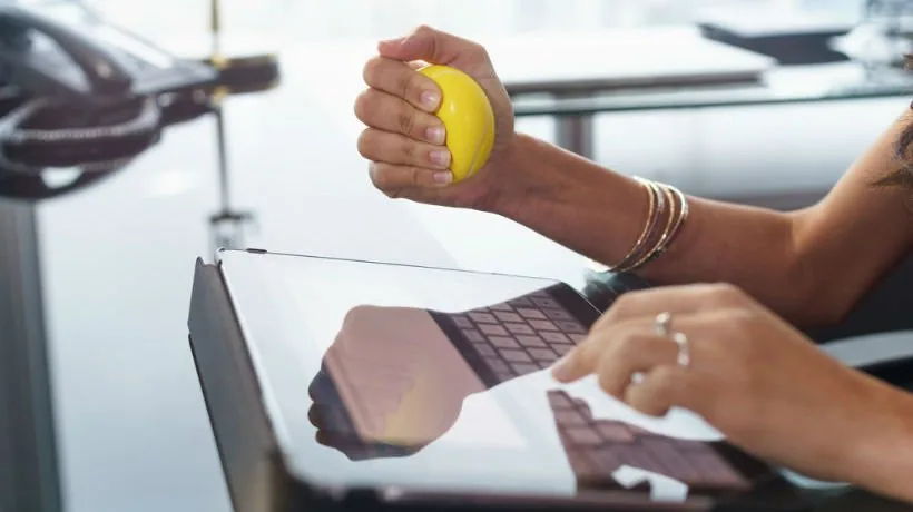 Persona utilizza una pallina antistress mentre lavora su un tablet in un contesto d’ufficio durante la formazione aziendale