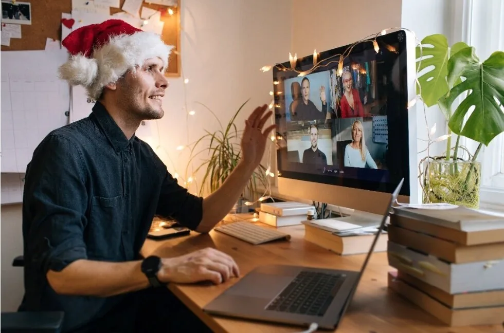 Persona con cappello di Babbo Natale partecipa a una videochiamata di lavoro festiva con colleghi