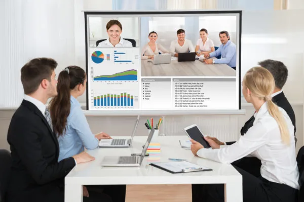 Gruppo di persone in ufficio che osserva una videoconferenza con grafici e dati sui costi della formazione elearning