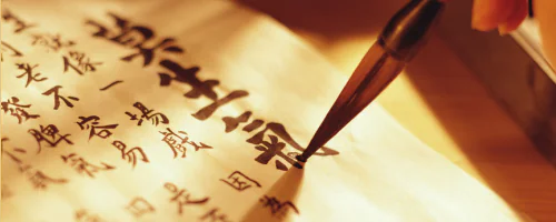 Pennello che scrive caratteri calligrafici su carta, simbolo di cura nella scrittura e attenzione allo stile