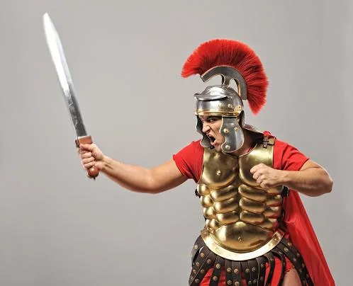 Uomo in armatura romana con elmo e spada sollevata, simbolo di prontezza e difesa nel contesto della selezione lavorativa