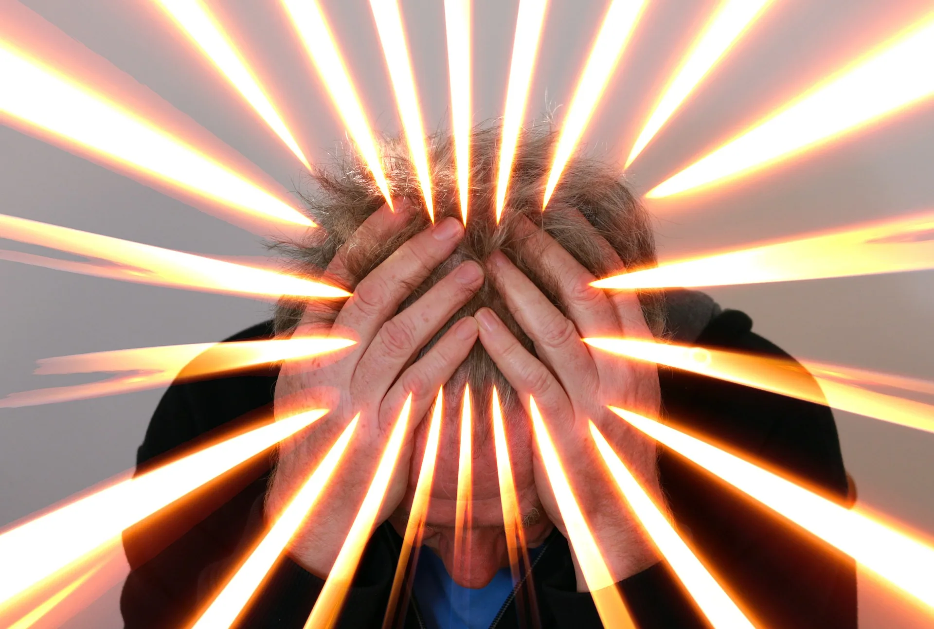 Persona con le mani sulla testa e raggi luminosi che simboleggiano stress e sovraccarico cognitivo nella formazione digitale