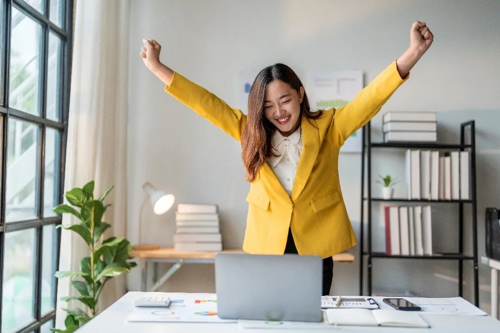 Donna felice con le braccia alzate davanti a un laptop, simbolo del successo di Articulate nei premi e-learning