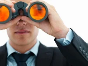 Persona in abito che osserva con un binocolo, simbolo della ricerca di feedback e supporto nello sviluppo elearning