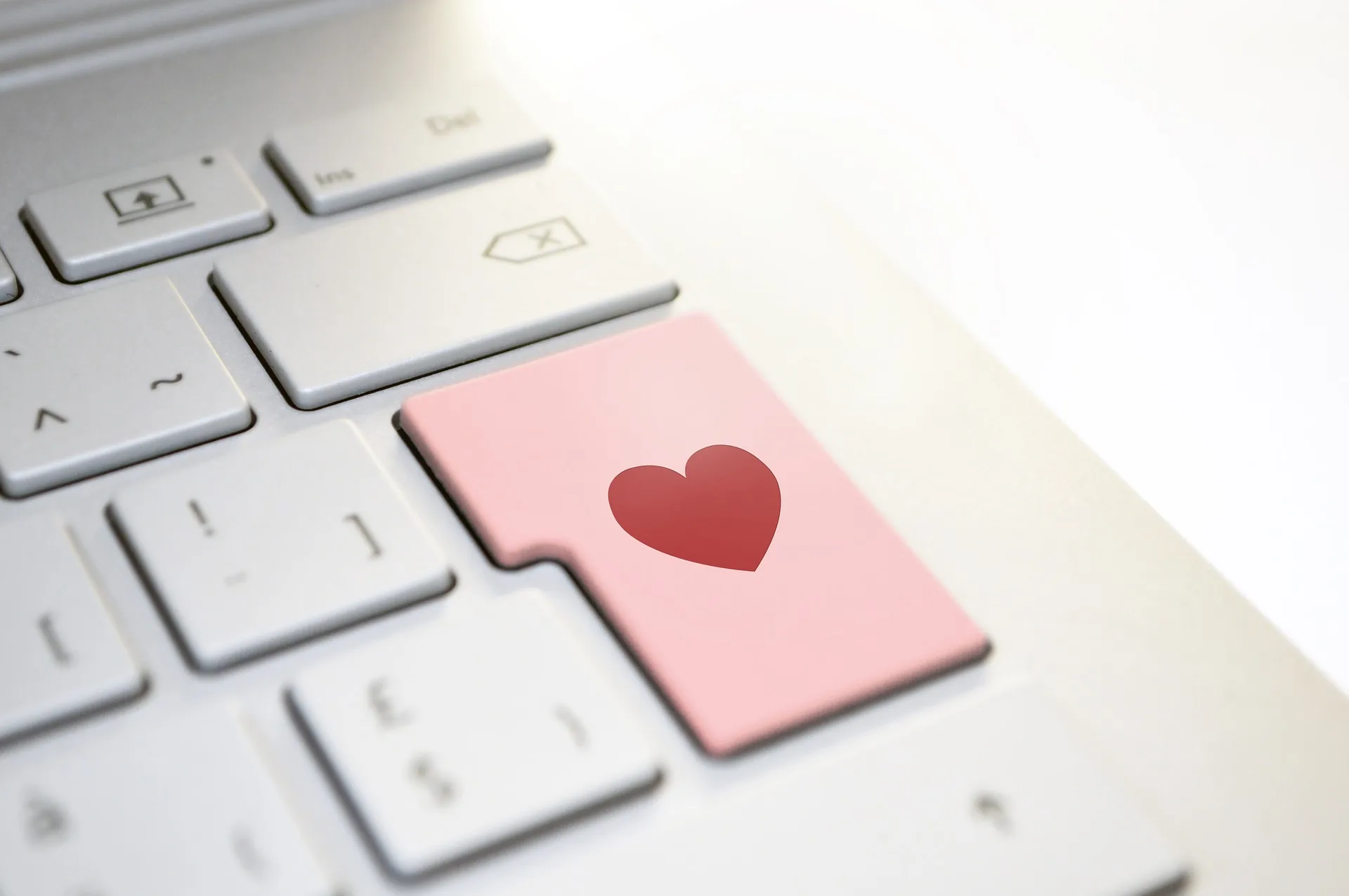 Tasto rosa con cuore rosso su tastiera bianca che simboleggia la passione nella progettazione di corsi digitali