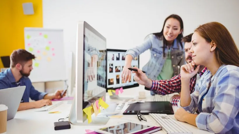 Gruppo di designer eLearning che collabora davanti a monitor con infografiche per facilitare la memorizzazione dei contenuti