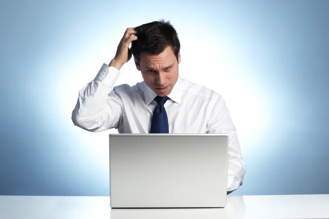 Uomo in camicia e cravatta davanti a un laptop con espressione perplessa, simbolo delle difficoltà nella localizzazione