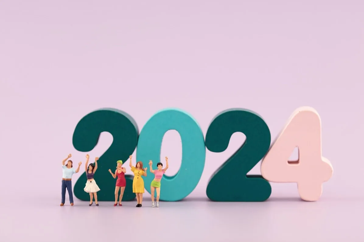 Sei figure in miniatura festeggiano davanti ai grandi numeri 2024 su sfondo lilla, simbolo di nuovi trend nell’e-learning