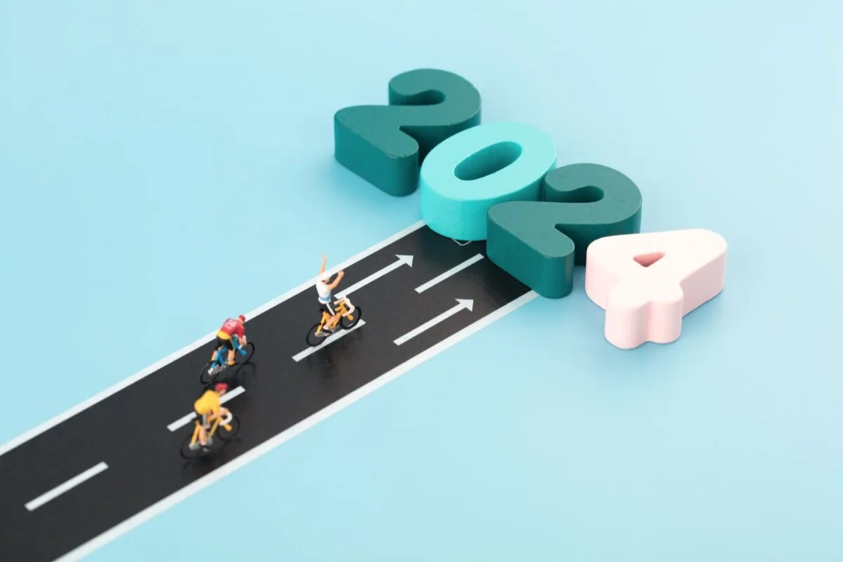 Tre ciclisti in miniatura percorrono una strada che conduce verso grandi numeri 2024, simbolo di innovazione nell’e-learning