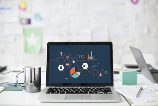 Laptop su una scrivania con grafici e icone di analisi dati sullo schermo, simbolo di valutazione della qualità elearning